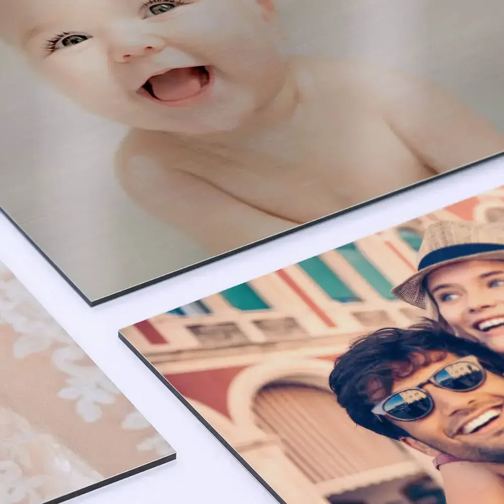 Three brushed aluminium prints stacked on a white surface showing the thin sandwich edge