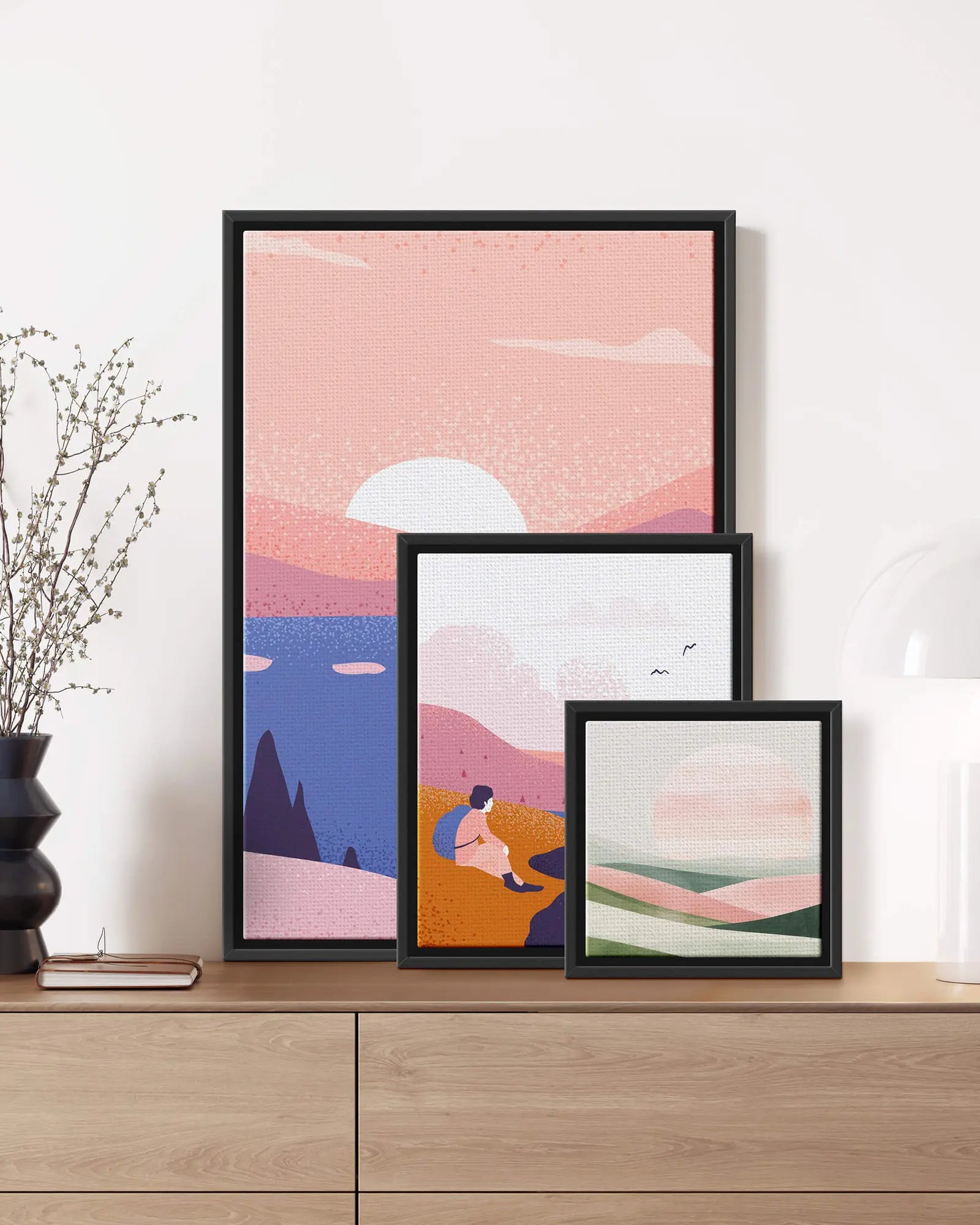 Three framed canvases in different sizes arranged on a sideboard
