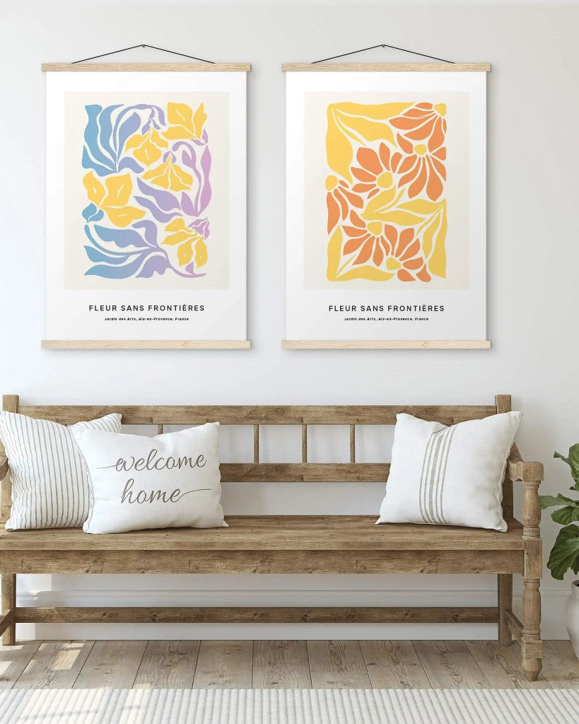 Two matte posters with wooden hangers hung side by side above a wooden bench