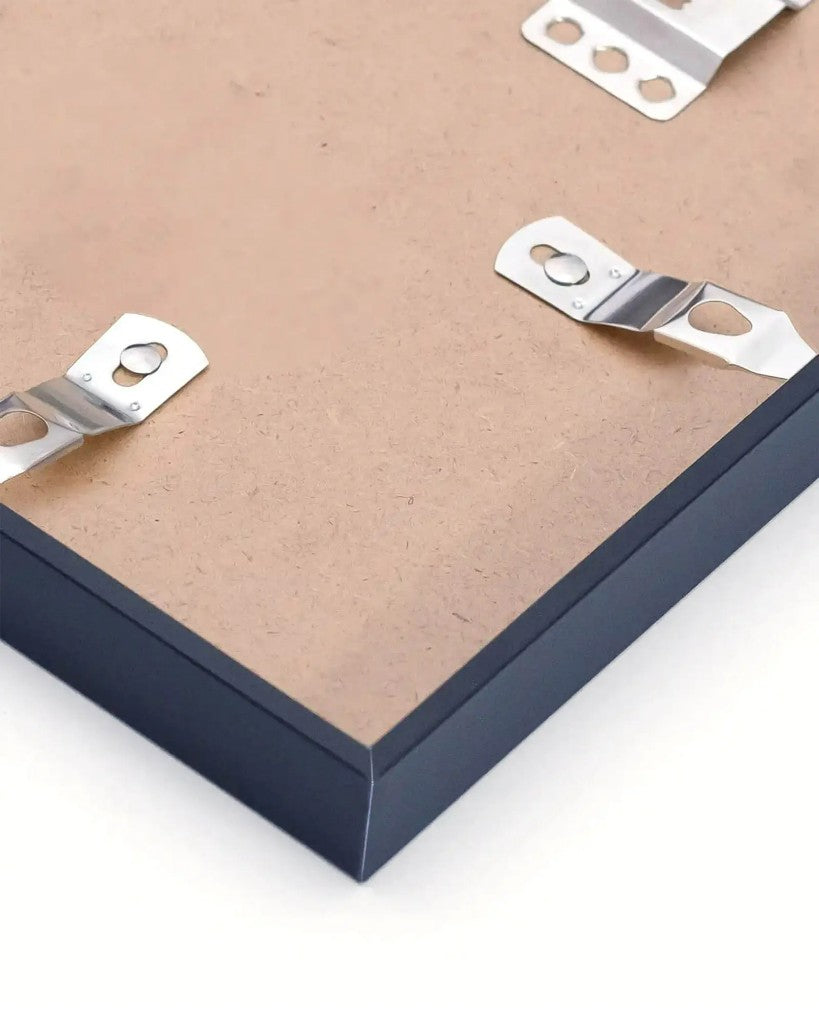 Back corner of a black metal frame showing backing board, clips and hanging plate